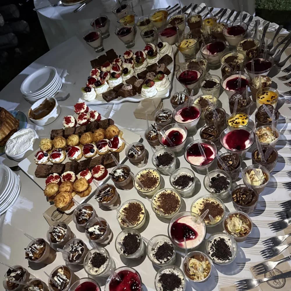 Mesa de postres variados de Confitería San Luis con vasitos individuales, cake pops y brownies